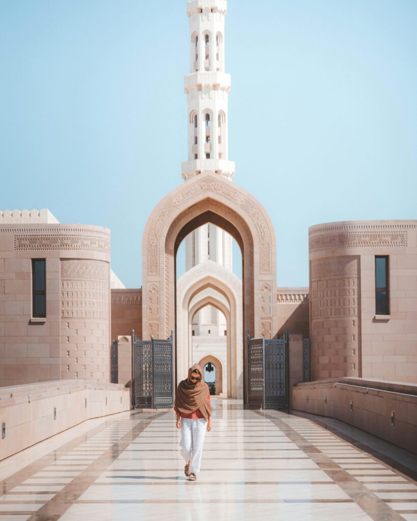 Person walking in front of a grand mosque showcasing beautiful modern Islamic architectural design.